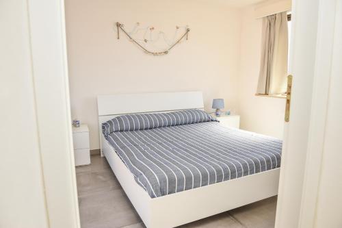 a bedroom with a white bed with a striped comforter at Casa Sarina in Marsala