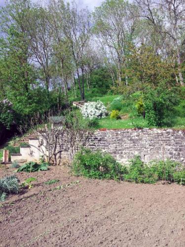 a garden with a stone wall and flowers at Gîte la Providence in Saint-Sernin-du-Plain