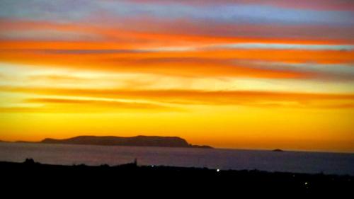 um pôr-do-sol sobre a água com uma montanha ao fundo em Sea View Home Suite em Hersonissos