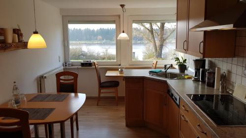 BreiholzにあるFerienwohnung mit wunderschönem Blick auf den Nord-Ostsee-Kanalのキッチン(シンク、テーブル付)、窓が備わります。