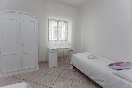 a white bedroom with a bed and a desk at Lulù Marin Casa Vacanze Praia a Mare in Praia a Mare