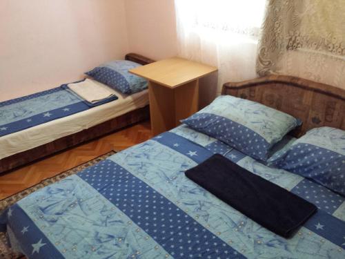 a bedroom with two beds and a wooden table at Apartments & Hostel Zdrava Hrana in Mostar