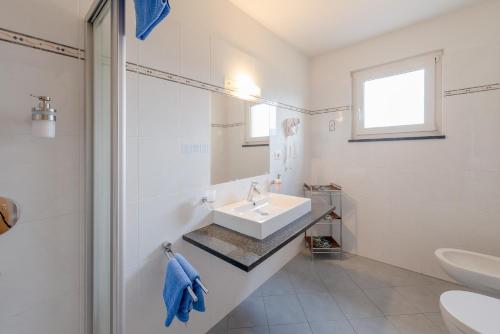 a white bathroom with a sink and a mirror at Garni Hotel Ritterhof in Termeno