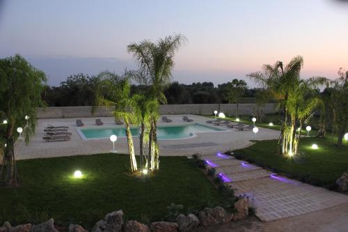 a pool at night with palm trees and lights at Agriturismo Paradiso in Parabita