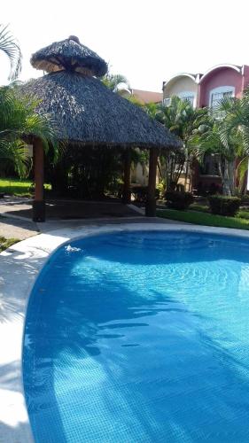a large blue swimming pool with a straw umbrella at Casa con alberca!! Ixtapa Zihuatanejo in Zihuatanejo
