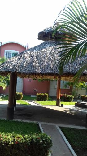 a straw roofed building with a palm tree at Casa con alberca!! Ixtapa Zihuatanejo in Zihuatanejo