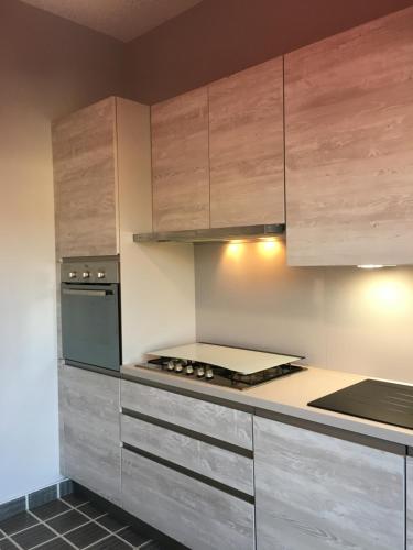 uma cozinha com armários de madeira e um forno com placa de fogão em Casa ad Alba em Alba