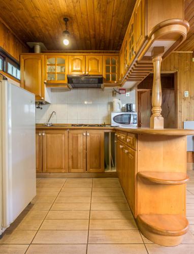 a kitchen with wooden cabinets and a white refrigerator at Cabañas Mapulay in Pucón