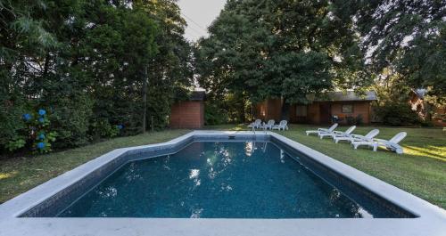 a swimming pool in a yard with chairs and a house at Cabañas Mapulay in Pucón