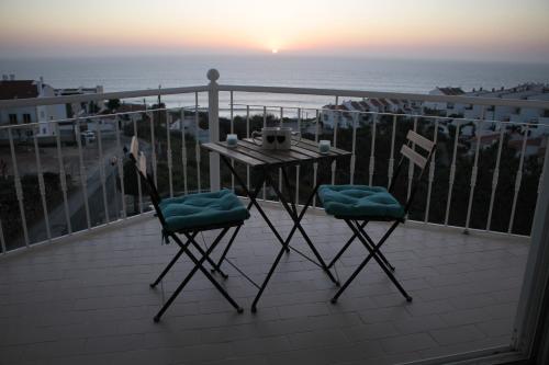 uma mesa e duas cadeiras numa varanda com o oceano em Ericeira Sunset Apartment na Ericeira