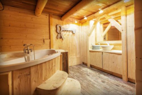 - une salle de bains pourvue d'une baignoire dans une cabine en bois dans l'établissement Le Cosy Lodge Départs ski Alpe d'Huez 2 Alpes La Grave et Col d'Ornon Détente Jacuzzi Piscine Sauna Bar Billard, au Bourg-dʼOisans