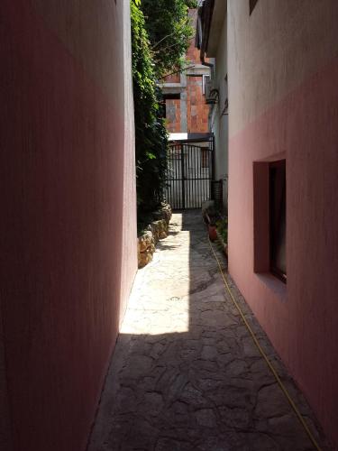 a narrow alley with a pink wall and a building at Apartments & Hostel Zdrava Hrana in Mostar