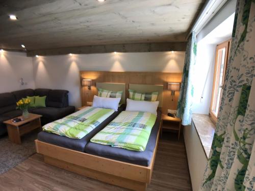 een kleine slaapkamer met een bed en een bank bij Gästehaus Amort Ferienwohnung in Ramsau