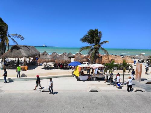 a group of people walking along a beach with umbrellas at Playa Linda Hotel in Progreso