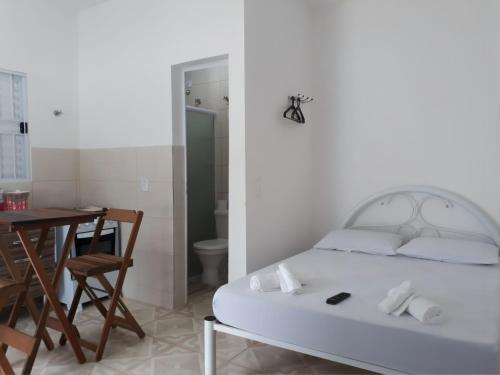 a bedroom with a bed and a table and a dining room at Estúdio em maresias com ar condicionado e piscina in Maresias