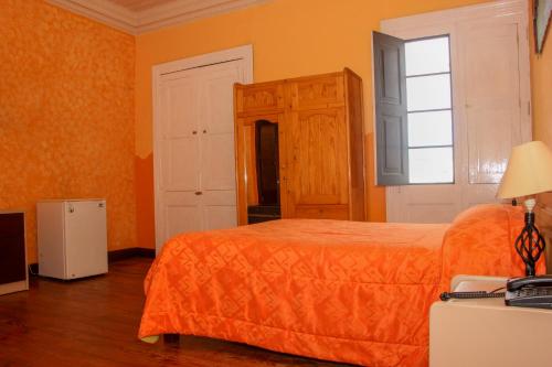 a bedroom with an orange bed and a window at Hostal Los Balcones de Moral y Santa Catalina in Arequipa