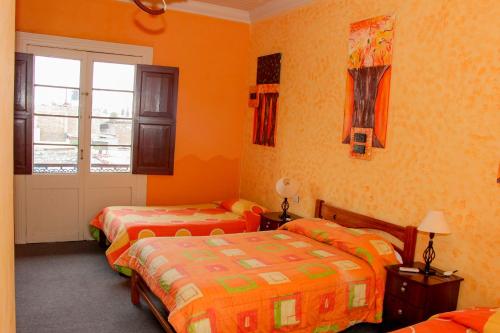two beds in a room with orange walls at Hostal Los Balcones de Moral y Santa Catalina in Arequipa