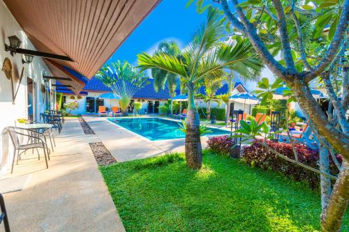 een villa met een zwembad en palmbomen bij Phuket Airport Hotel - SHA Extra Plus in Nai Yang Beach