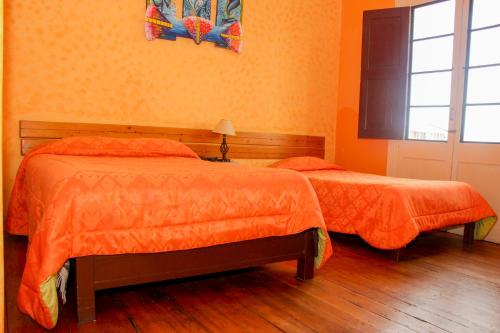 two beds in a room with orange walls at Hostal Los Balcones de Moral y Santa Catalina in Arequipa