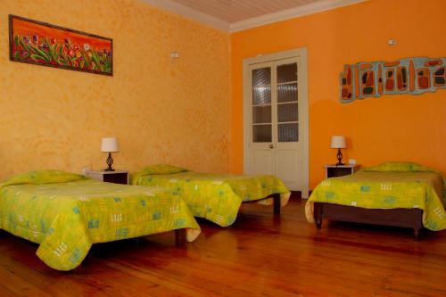 two beds in a room with orange walls at Hostal Los Balcones de Moral y Santa Catalina in Arequipa
