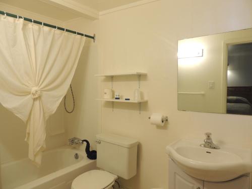 Baño blanco con aseo y lavamanos en 100 Mile Motel & RV Park en One Hundred Mile House