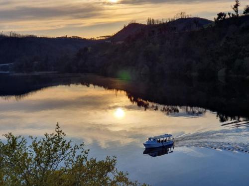 a small boat on a lake at sunset at Hotel Rural Quinta da Conchada in Aguieira