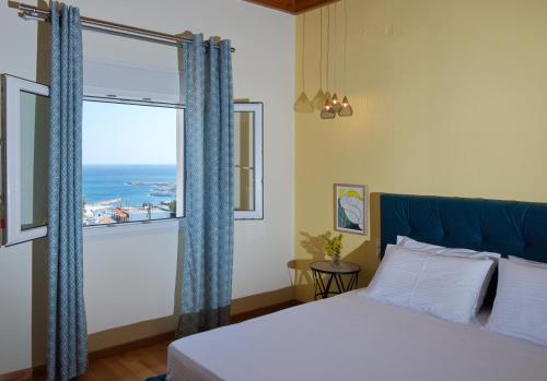a bedroom with a bed and a window with the ocean at Lidromi Home (Sky) in Patitiri