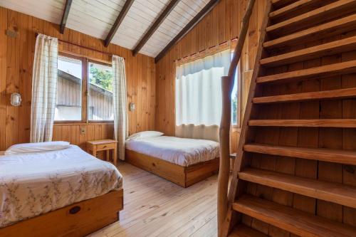 a log cabin bedroom with two beds and a staircase at Cabañas Mapulay in Pucón
