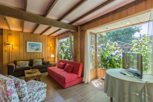 a living room with a red couch and a table at Cabañas Mapulay in Pucón