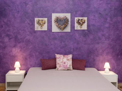 a bedroom with purple walls and a bed with two lamps at Bouganville House in Zafferana Etnea