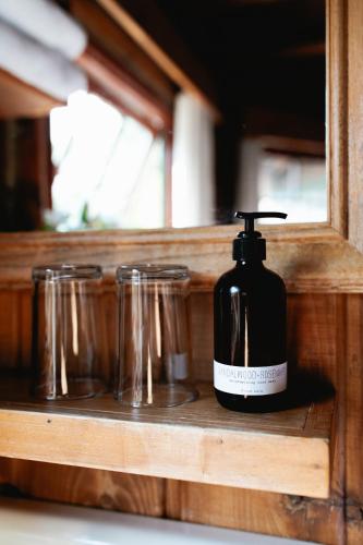 a bottle of soap sitting on a shelf with glasses at Captain Whidbey in Coupeville