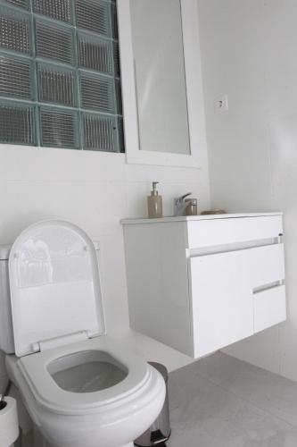 une salle de bain blanche avec toilettes et lavabo dans l'établissement Apartamento Júnior, à Praia