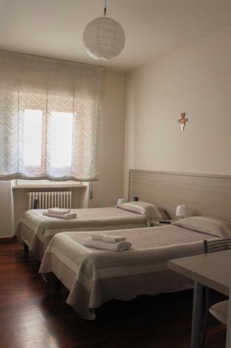 two beds in a room with two windows at B&B Domus Benedicta in Assisi