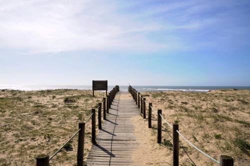 a wooden boardwalk leading to the ocean on a beach at Beach House, Labruge, Porto in Labruge