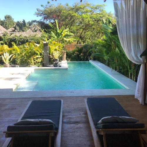 a swimming pool with two loungers in a backyard at Lua Villas in Santa Teresa Beach