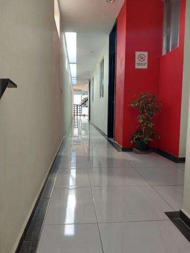 an empty hallway with a red wall and a plant at Hotel del Rosario in Zacatlán