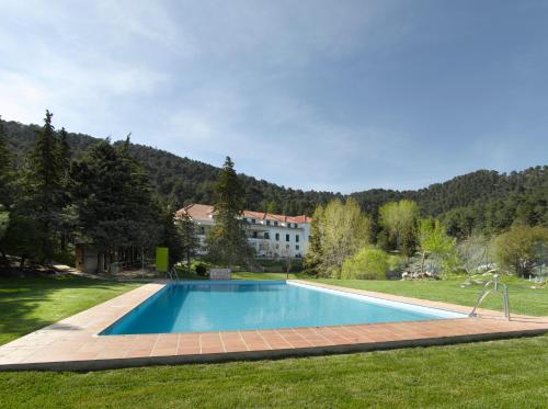a swimming pool in a yard with a house in the background at Parador de Cazorla in Cazorla