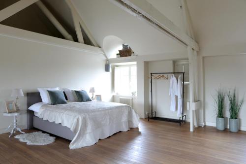 a white bedroom with a bed and a large window at The Loft in Melsele