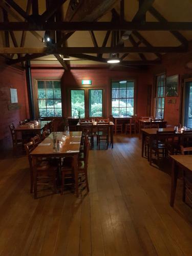 um restaurante com mesas e cadeiras de madeira e janelas em Corinna Wilderness Village em Corinna