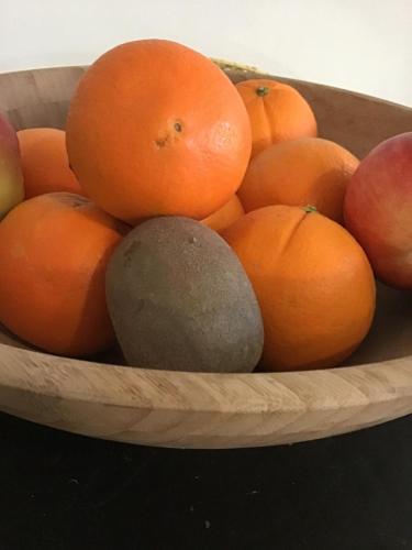 a wooden bowl of oranges and apples on a table at Hotel La Casa in Le Barcarès