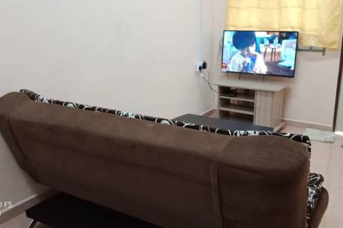 a brown couch in a living room with a tv at Desa Impian Tanah Merah Homestay in Tanah Merah