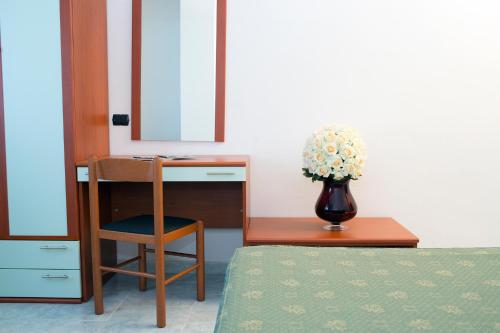 a bedroom with a desk and a vase of flowers at Albergo Villa Marchese in San Giovanni Rotondo