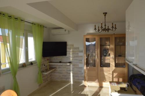 een woonkamer met een televisie en groene gordijnen bij Apartament M & E in Vodice