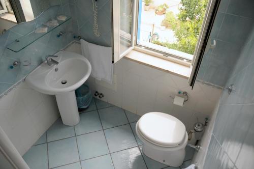 a bathroom with a sink and a toilet and a window at Hotel Villa Del Mare in Bacoli