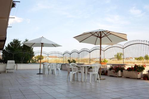 a patio with white tables and chairs and umbrellas at Albergo Villa Marchese in San Giovanni Rotondo