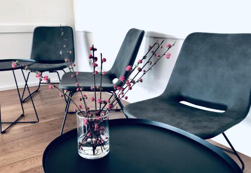 a glass vase with flowers on a table with chairs at Weingut Gehlen-Cornelius in Brauneberg