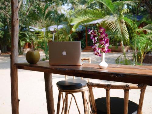 a wooden table with a laptop and flowers on it at Palm Forest Palolem in Palolem