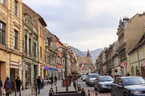 a city street with cars and people walking down the street at Strada Mureșenilor - Savas Apartament in Braşov