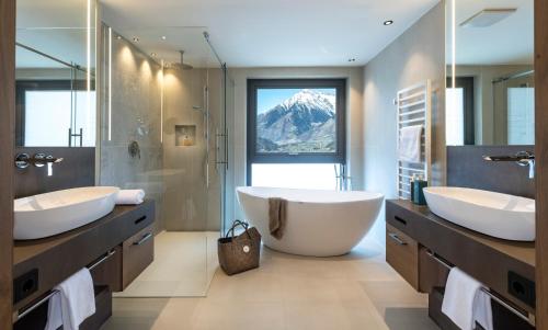 un bagno con due lavandini e una grande vasca di Hotel Sonnbichl a Tirolo