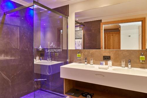 a bathroom with two sinks and a shower at Hotel Sassongher in Corvara in Badia